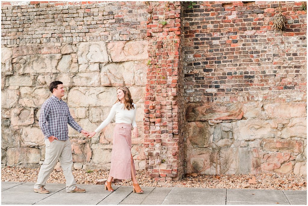 engagement session couple at tredegar ironworks brick wall near belle isle in richmond virginia