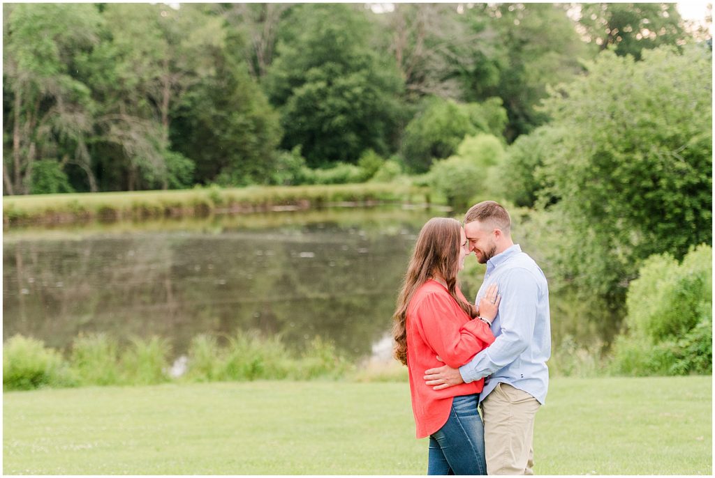 engagement sessions with couple at edgewood barn in front of lake hugging each other
