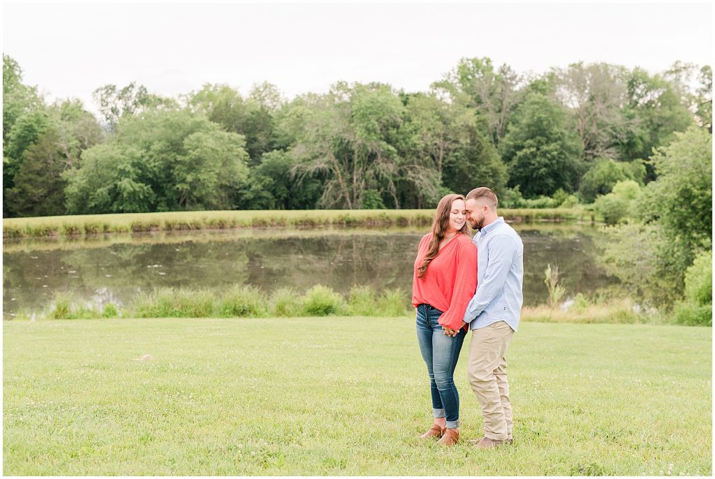 engagement sessions with couple at edgewood barn in front of lake laughing