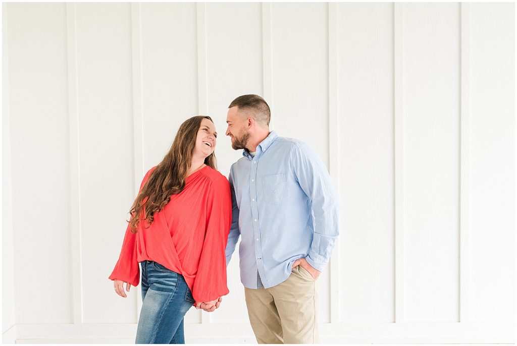 engagement session couple at edgewood barn at overhang with white wall behind