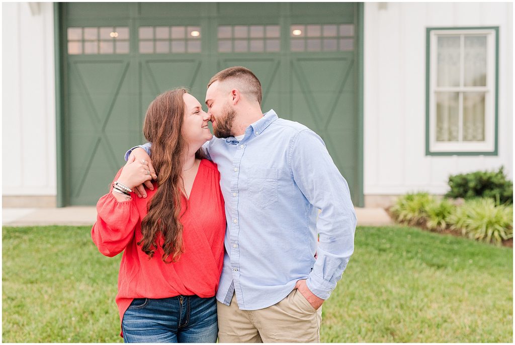 engagement session couple in front of green barn doors at edgewood wedding venue
