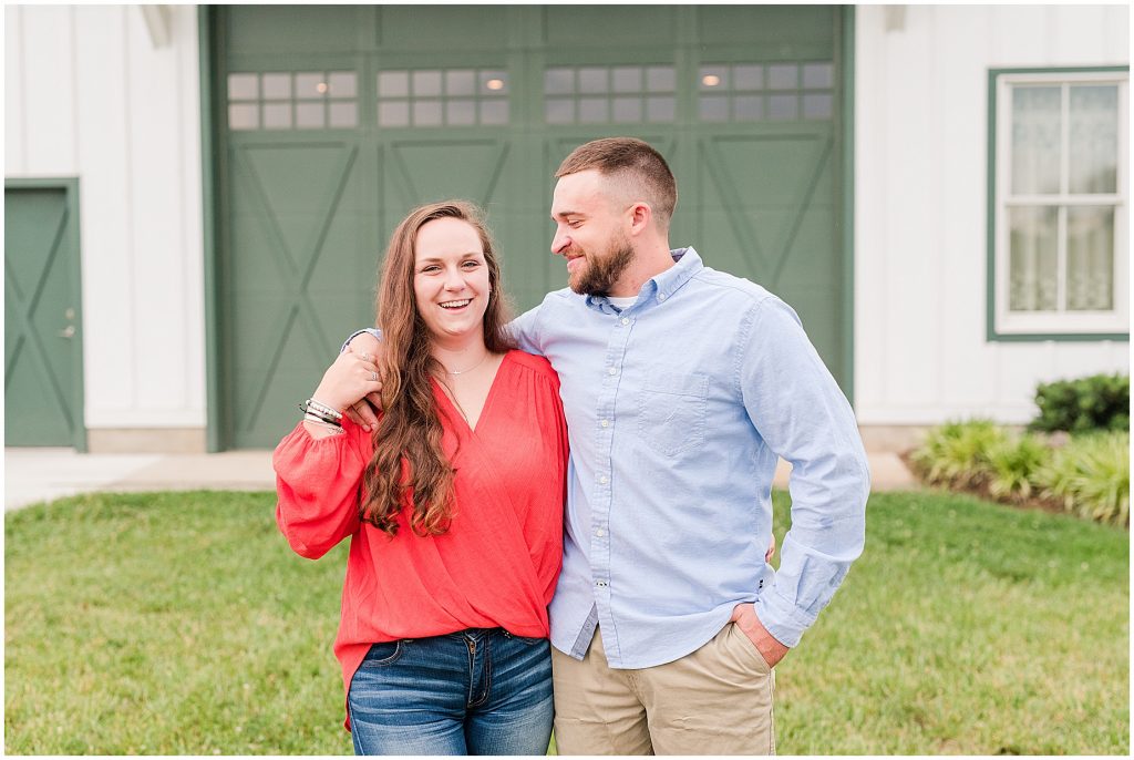 engagement couple in red and blue in front of barn doors at edgewood