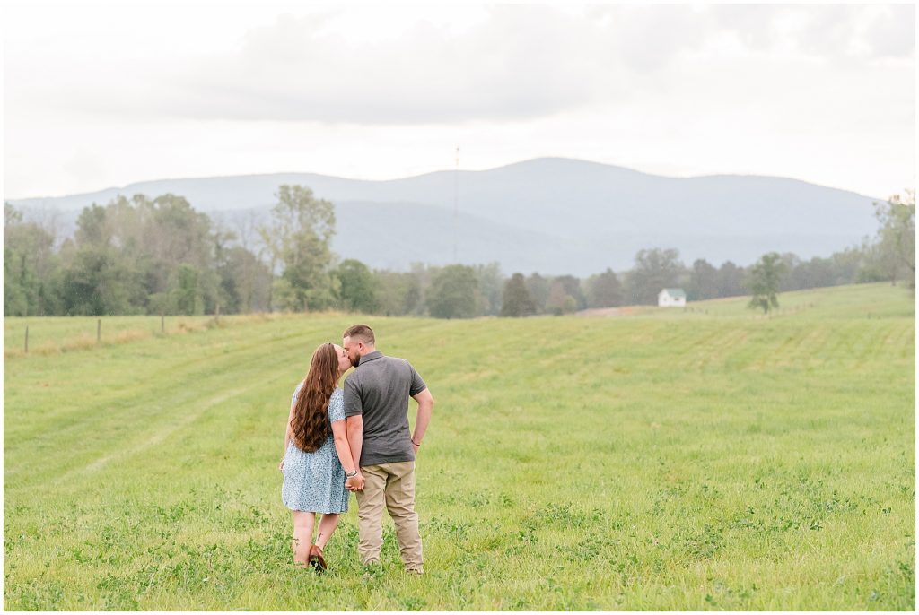 engagement session couple standing in field at edgewood barn with blue ridge mountains behind