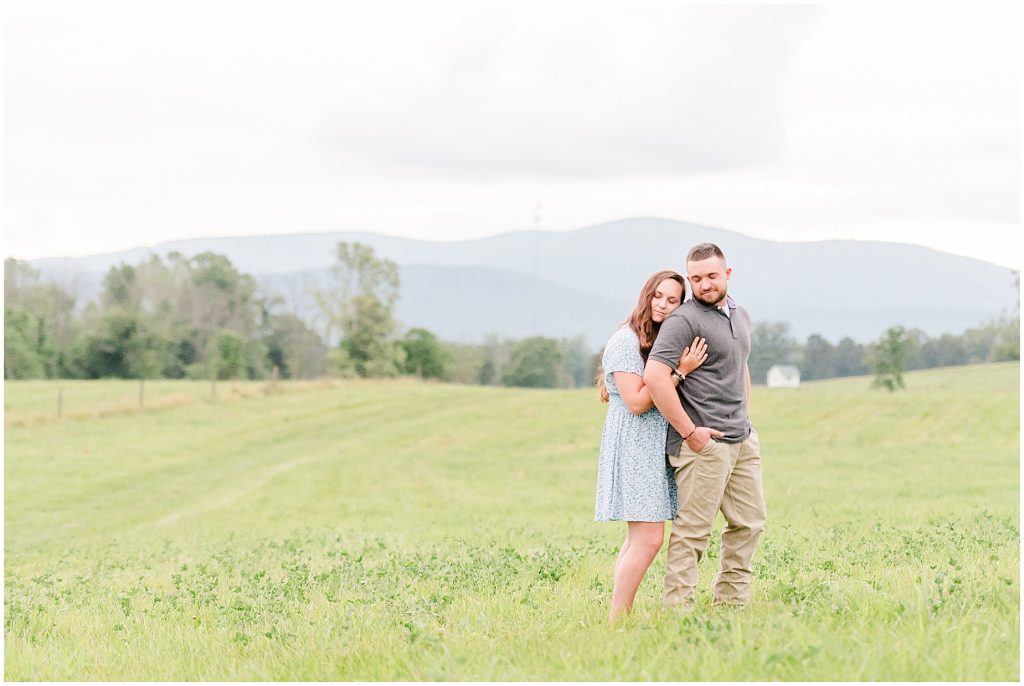 engagement session couple hugging in field at edgewood barn venue with shenandoah mountain view