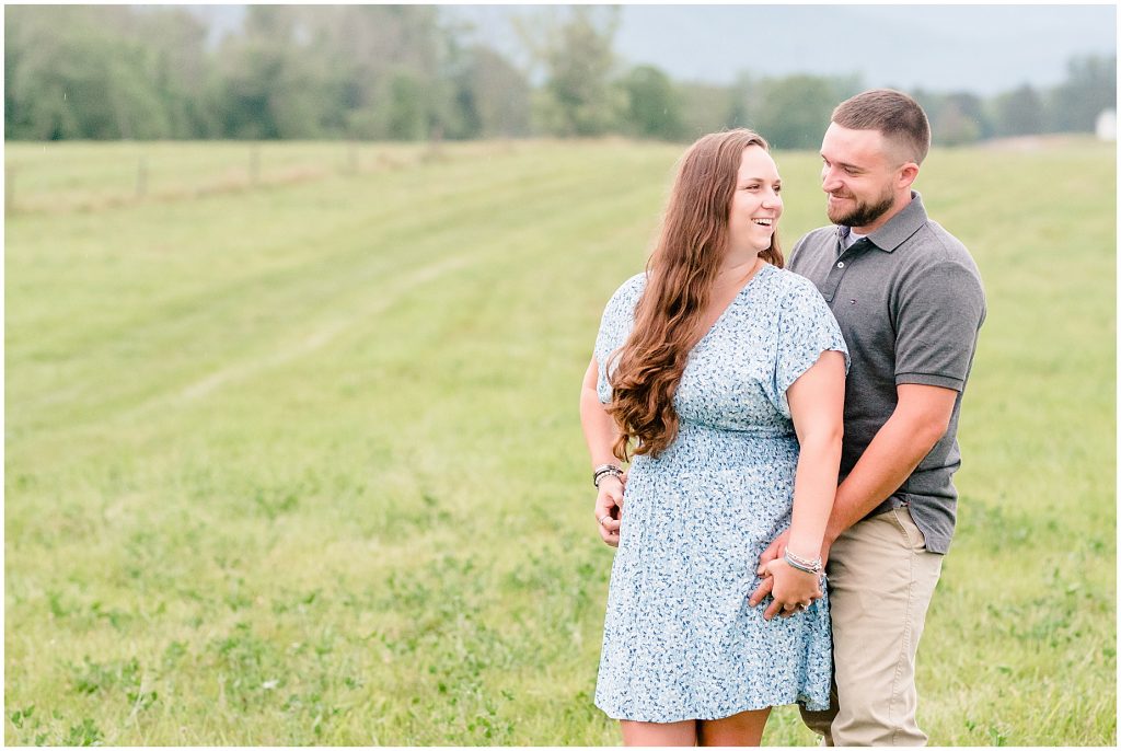 engagement session couple standing in field at edgewood barn with blue ridge mountains behind