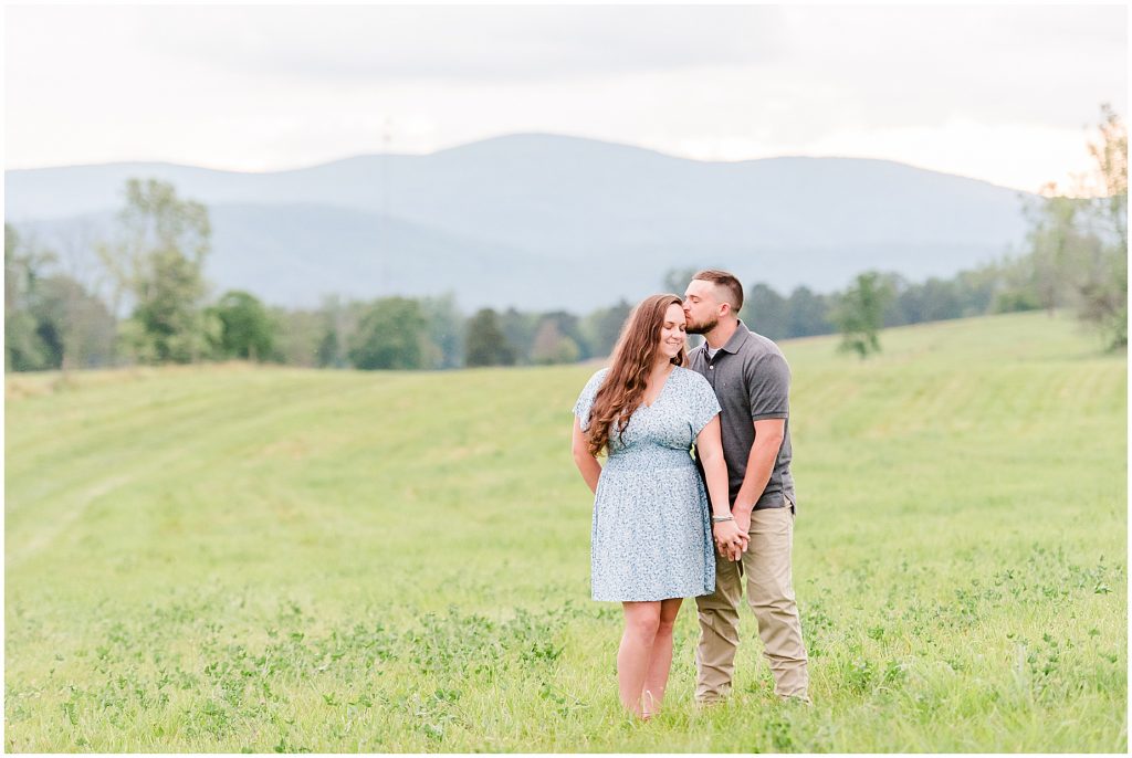engagement session couple standing in field at edgewood barn venue with mountain view