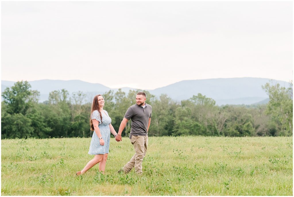 engagement session couple walking in field at edgewood barn venue with shenandoah mountain view
