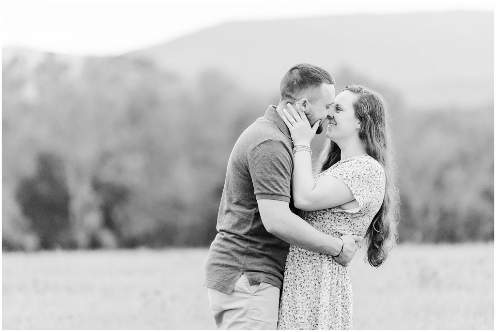 engagement session couple standing in field at edgewood barn venue with mountain view in black and white