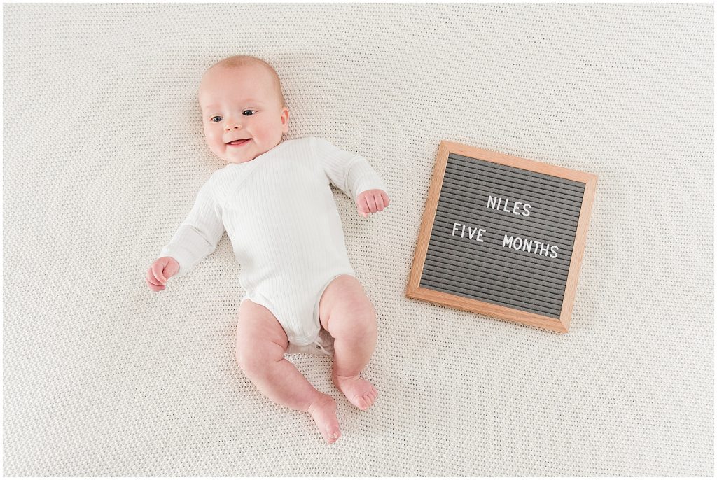 Richmond photographers niles lying on white bed with letter board