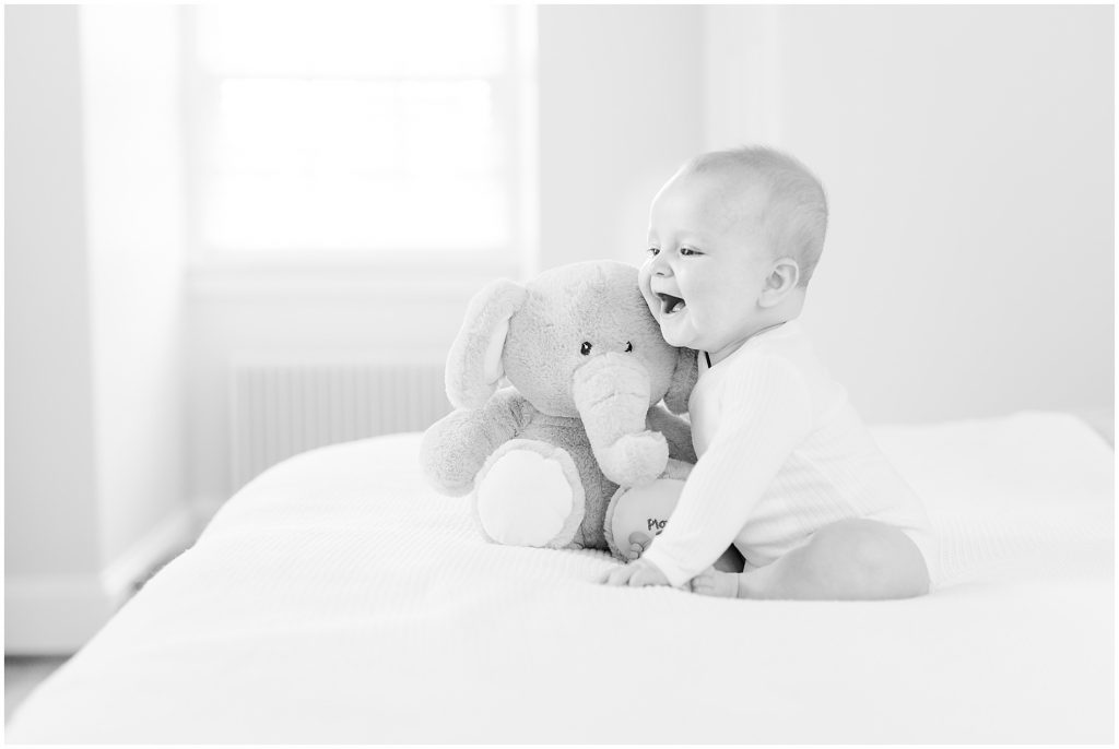 Richmond photographers niles turned 6 months sitting on bed with elephant