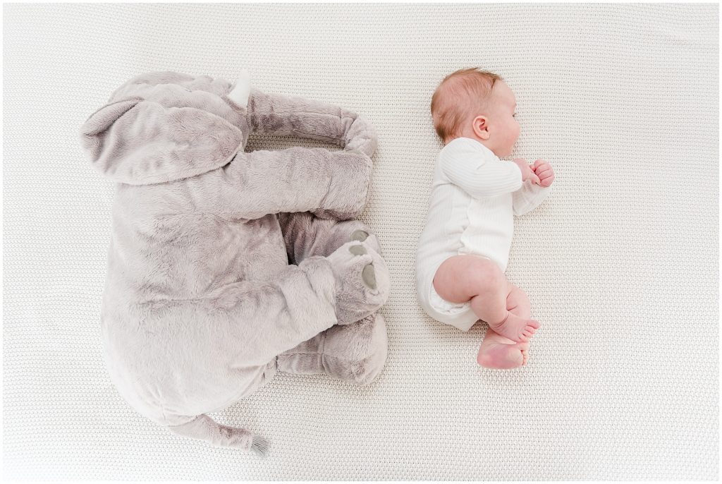 Richmond photographers niles lying to the side on bed at 3 months with elephant