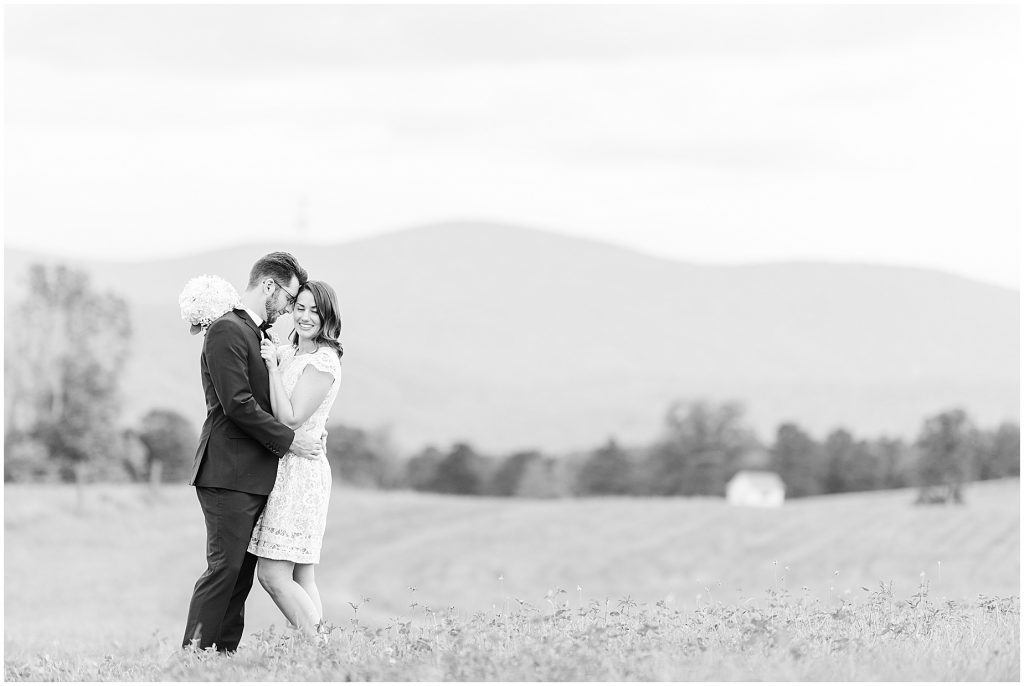 Bride and groom in open field with mountains behind them at the barn at edgewood after coronavirus mini wedding