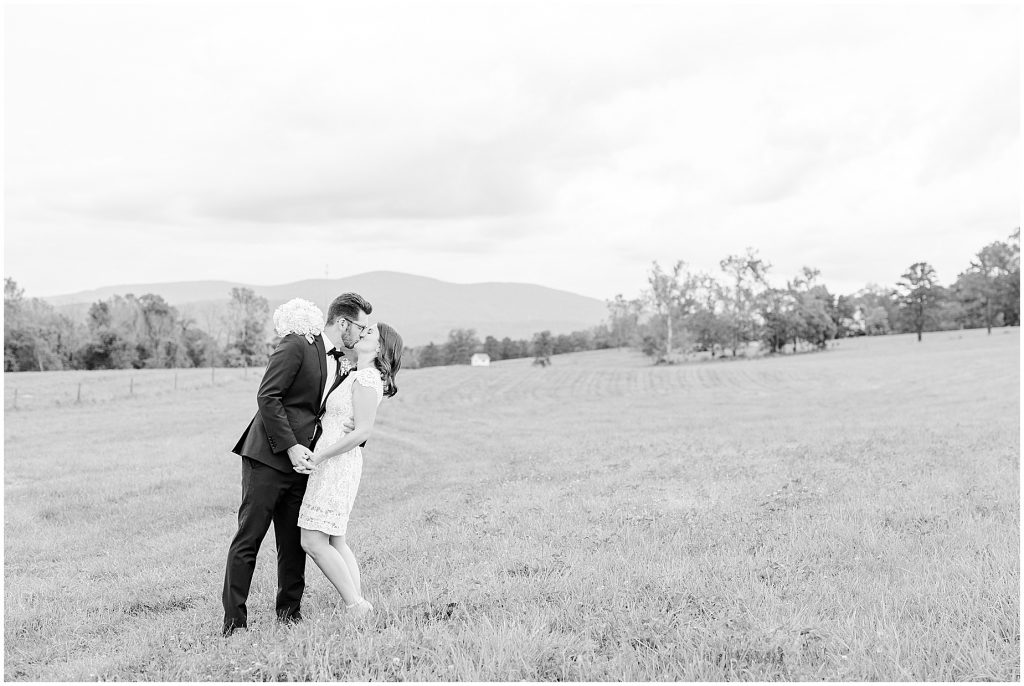 Bride and groom sharing a kiss in open field at the barn at edgewood after mini wedding