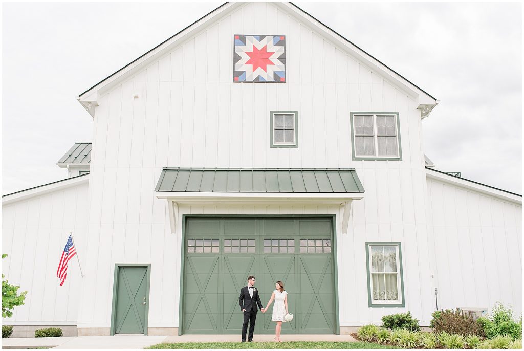 Bride and groom standing in front of barn at edgewood after coronavirus mini wedding