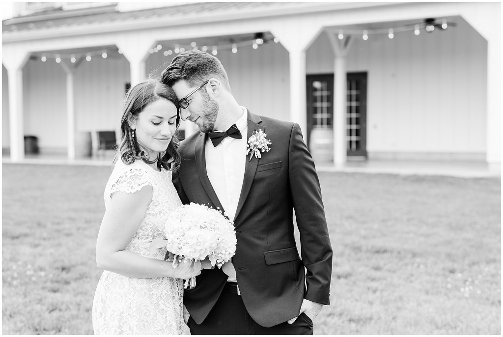Bride and groom sharing a moment in front of barn at edgewood after coronavirus mini wedding