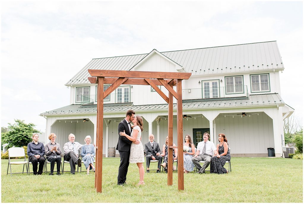 barn at edgewood coronavirus mini wedding bride and groom sharing first kiss with barn in background