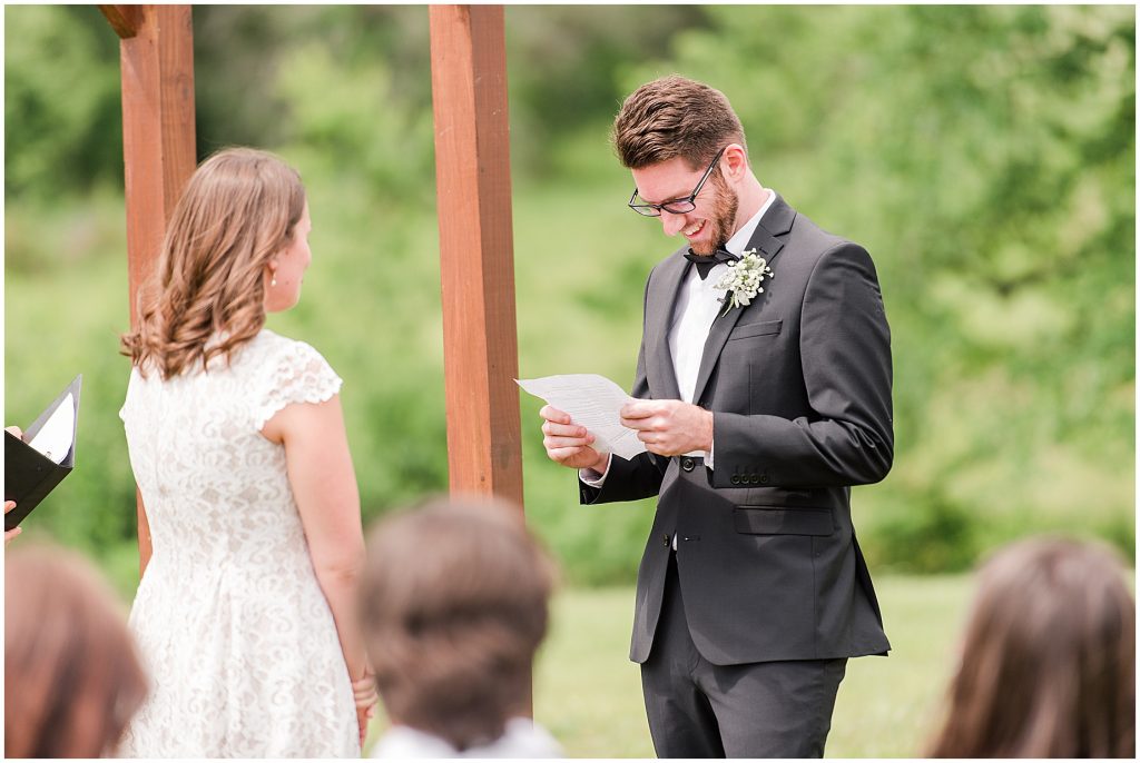 barn at edgewood coronavirus mini wedding groom reading vows in field
