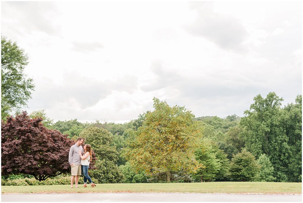 maymont park engagement session couple standing on hill with trees behind