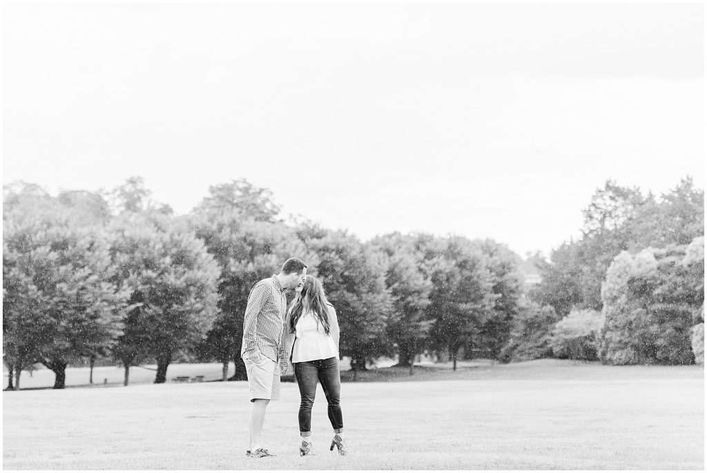engagement session couple at maymont park kissing in open field while it rains