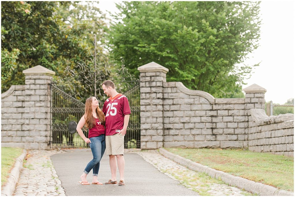 rainy engagement session couple walking at maymont park gate in virginia tech gear