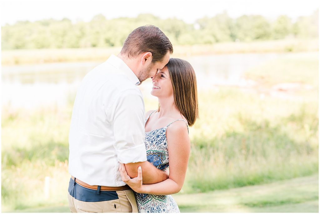 sunny Lansdowne resort engagement session couple eskimo kissing on golf course in Leesburg