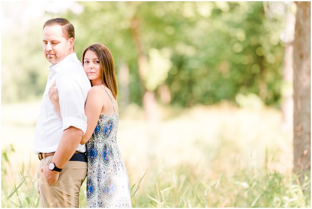 sunny Lansdowne resort engagement session couple in grassy field at a golf course in Leesburg