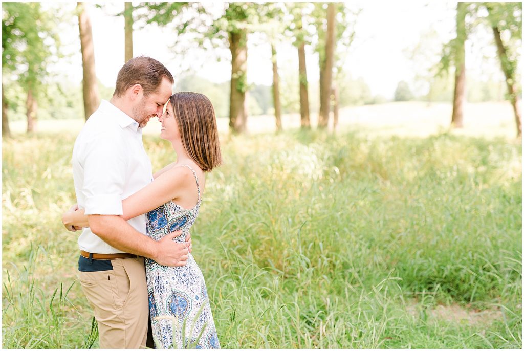 sunny Lansdowne resort engagement session couple hugging in grassy field at a golf course in Leesburg