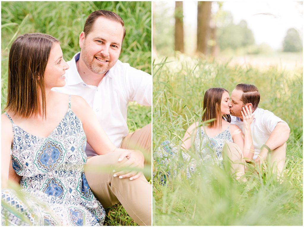 sunny Lansdowne resort engagement session couple sitting and kissing in a grassy field at a golf course in Leesburg