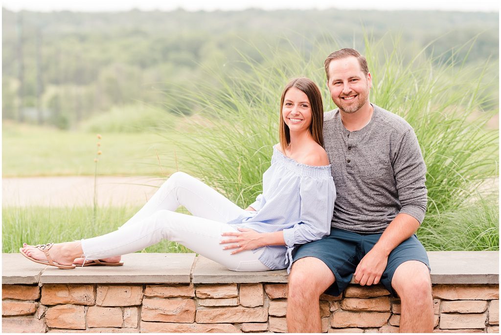 Lansdowne golf resort engagement couple sitting on stone wall at a golf course