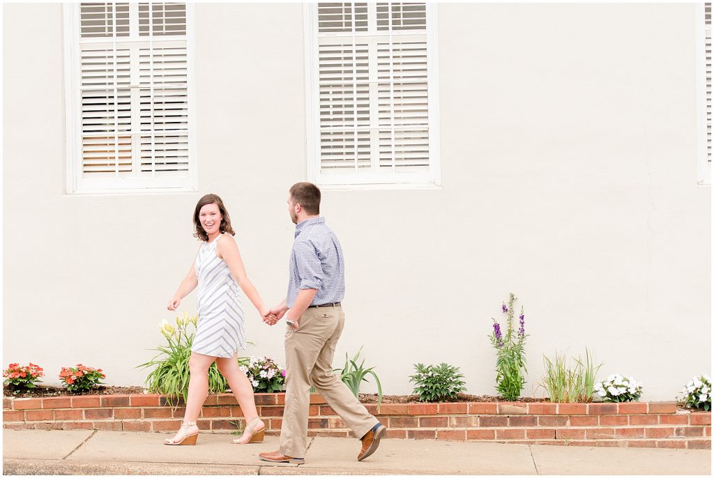 richmond engagement couple at Libbie & Grove area walking with plain wall behind