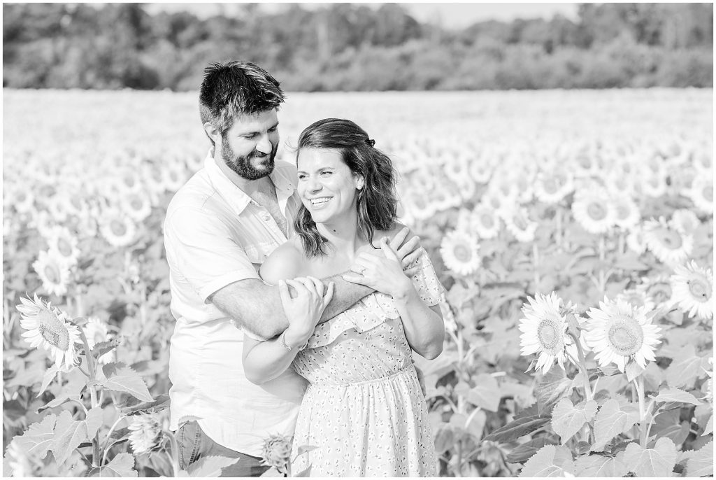engaged couple in sunflower field hugging black and white