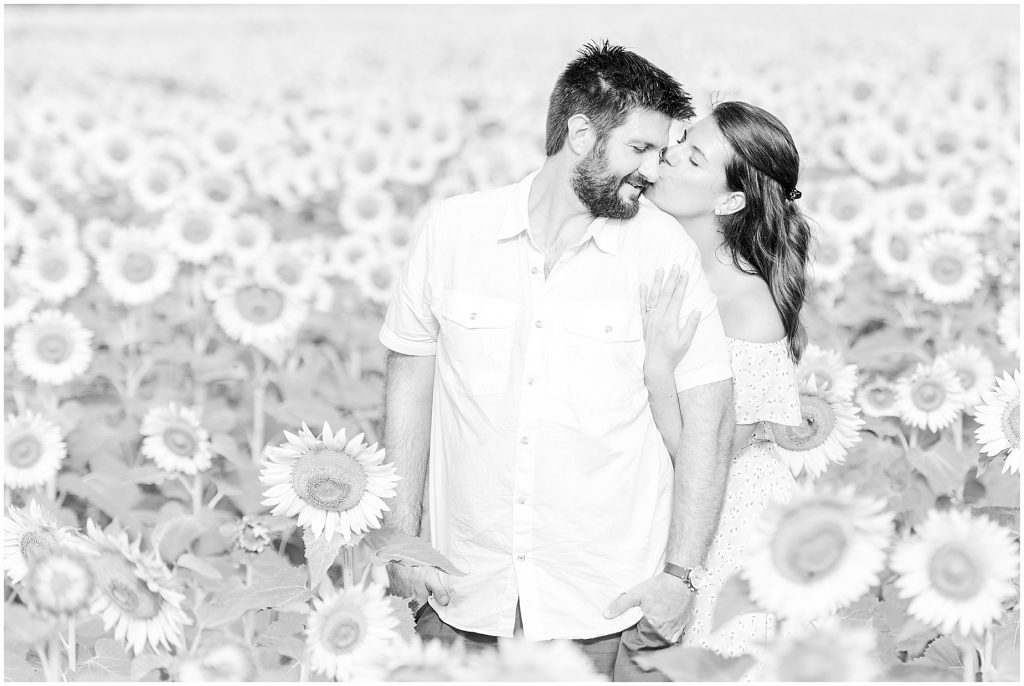 engaged couple kissing in sunflower field black and white