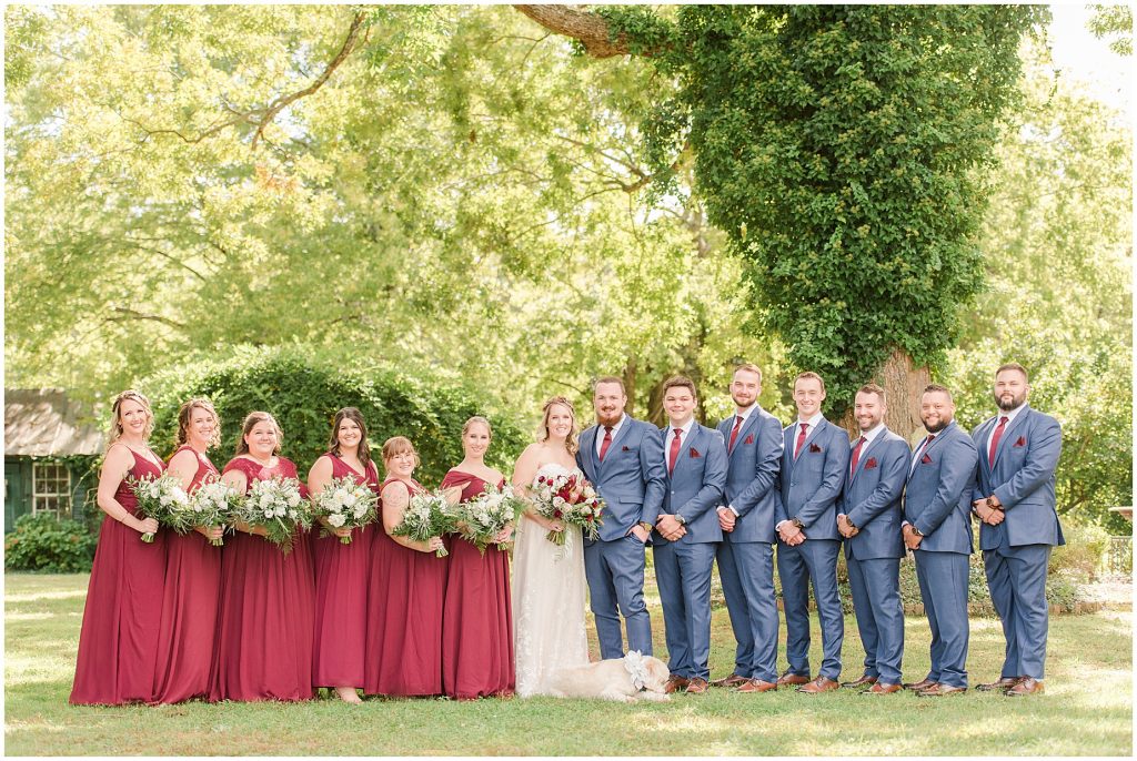 bridal party at wisteria farms blue suits and red dresses