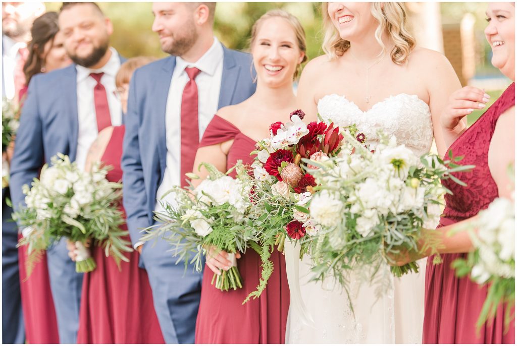 bridal party at wisteria farms blue suits and red dresses