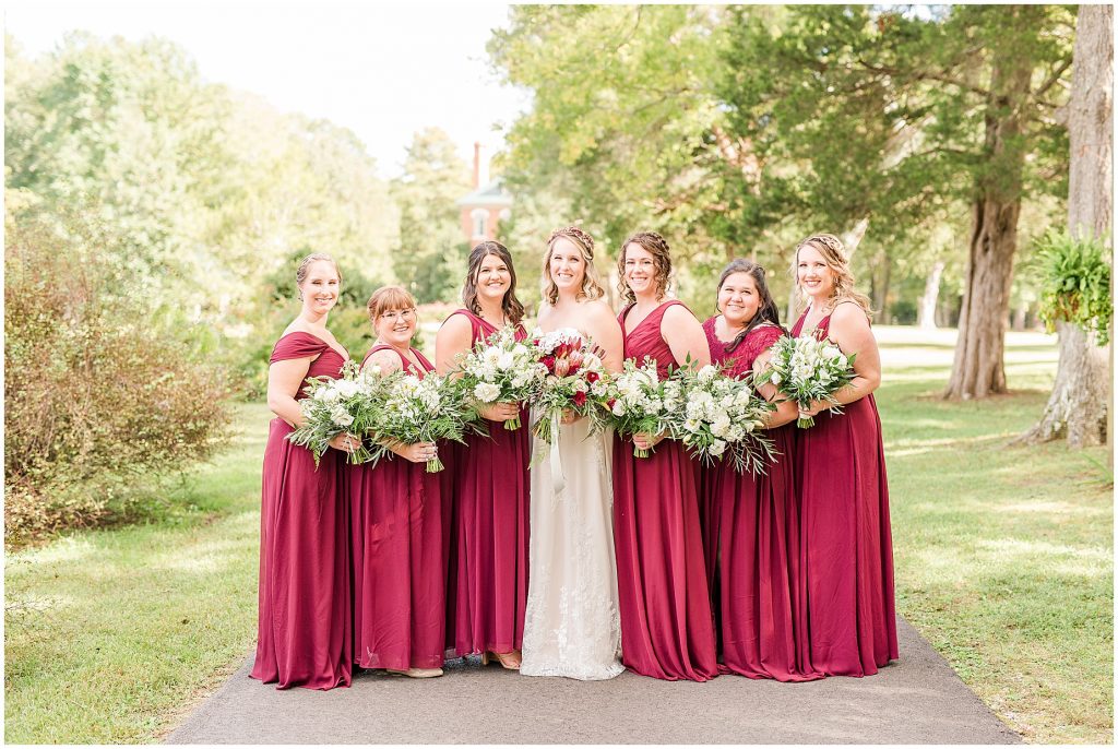 bridal party at wisteria farms blue suits and red dresses