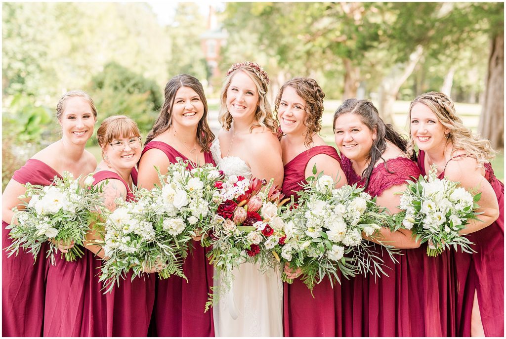 bridal party at wisteria farms blue suits and red dresses
