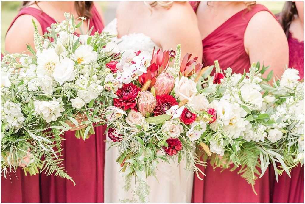 bridal party at wisteria farms blue suits and red dresses