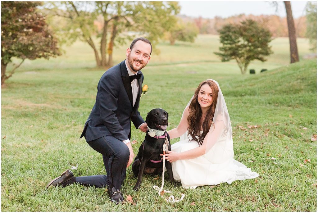 bride and groom with their black lab dog at wedding