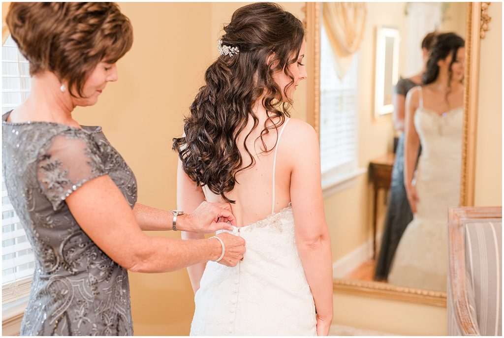 mother helping bride into wedding dress at amber grove bridal suite