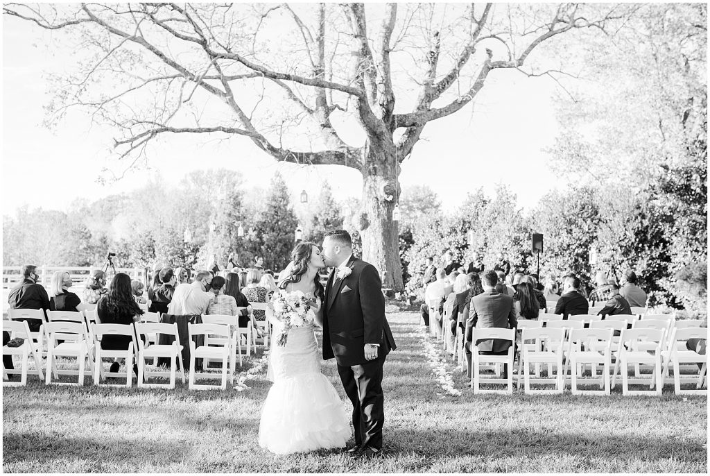 ceremony at amber grove virginia wedding venue bride and groom kissing in black and white