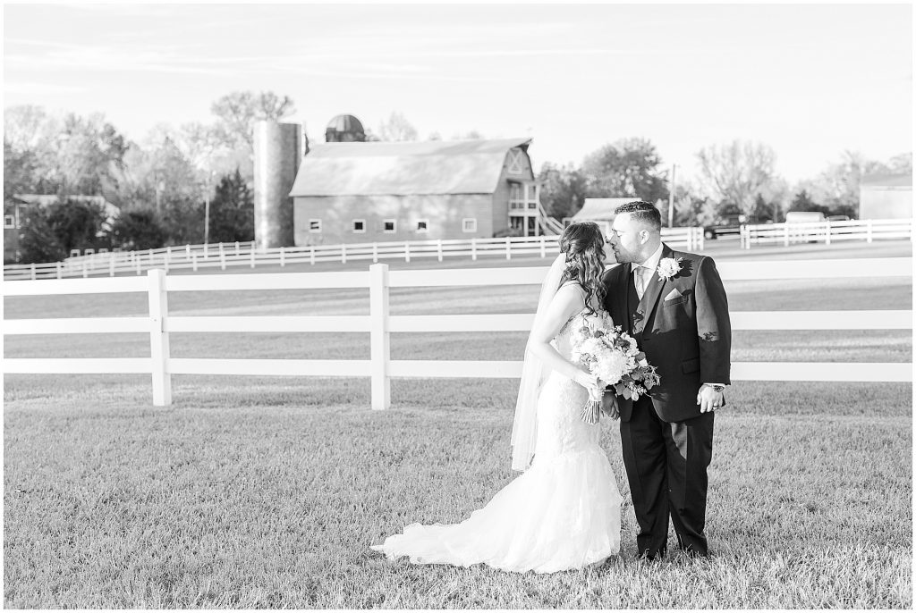 bride and groom standing in field with barn at amber grove richmond virginia