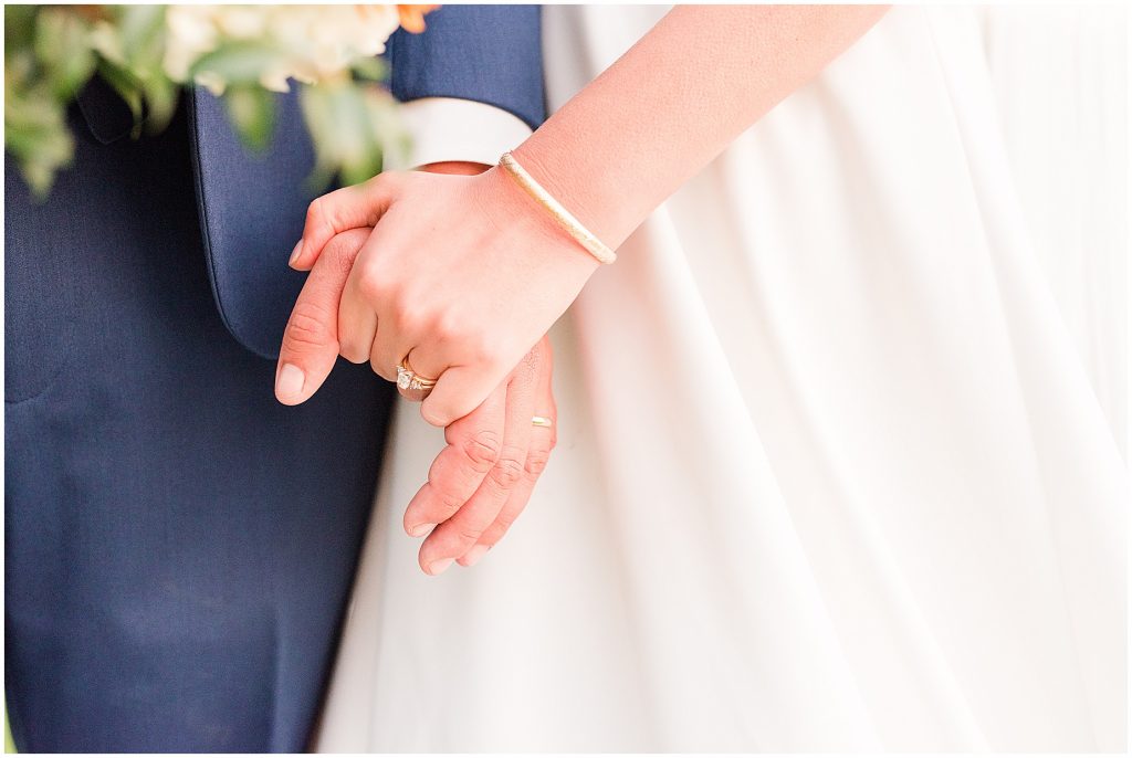 close up detail of wedding couple holding hands with ring sparking