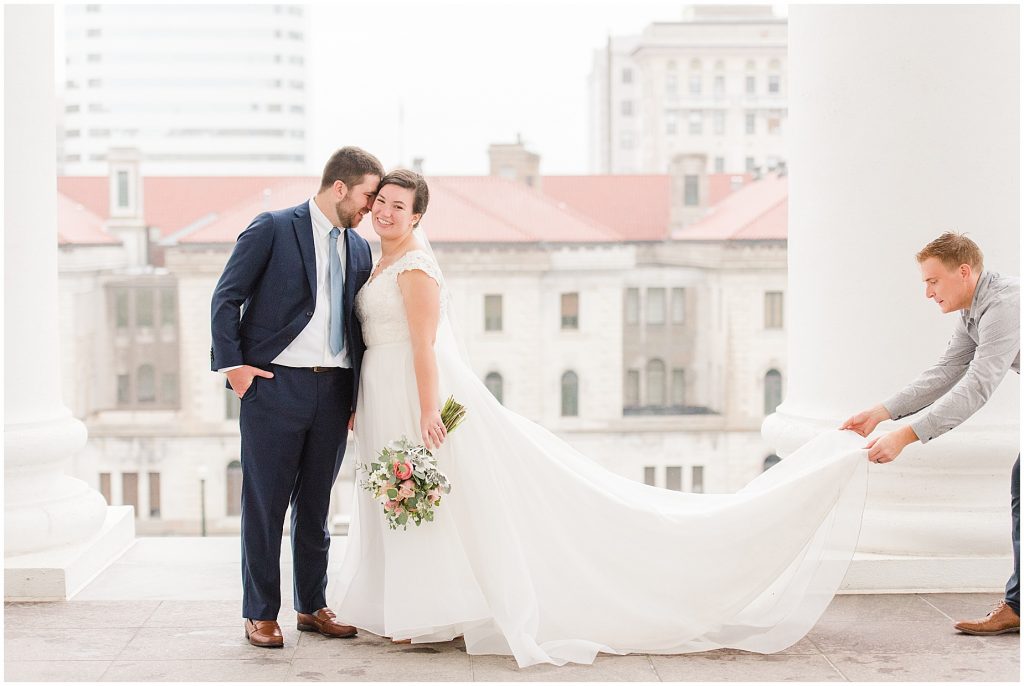photographer fluffing wedding dress with bride and groom at the virginia Capitol Building in richmond