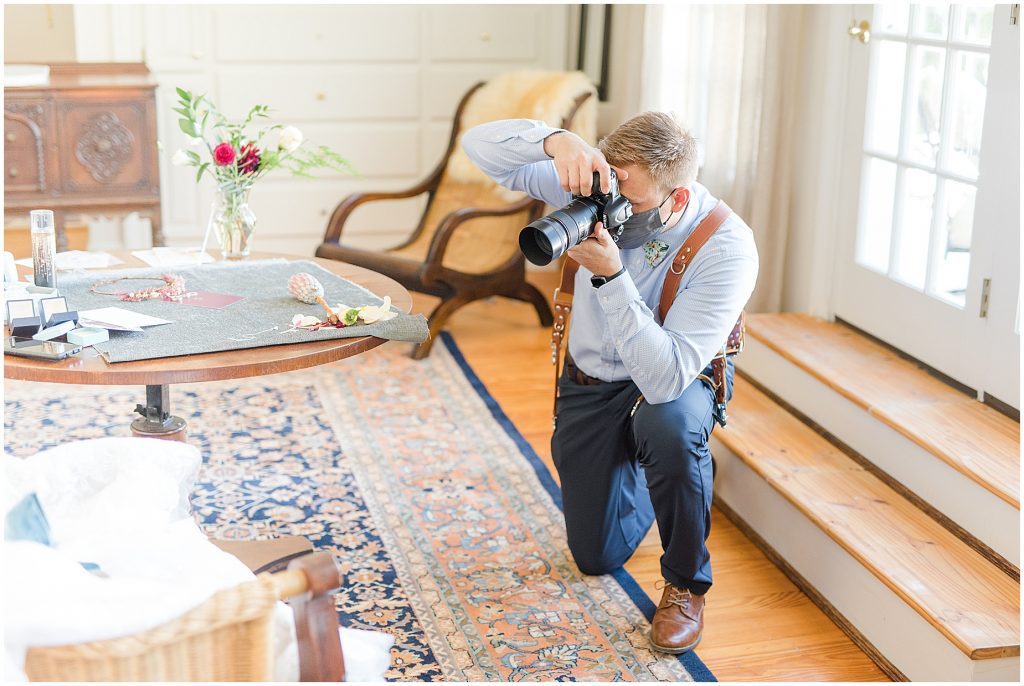 photographer taking details of flowers and stationery at wedding at Wisteria Farms