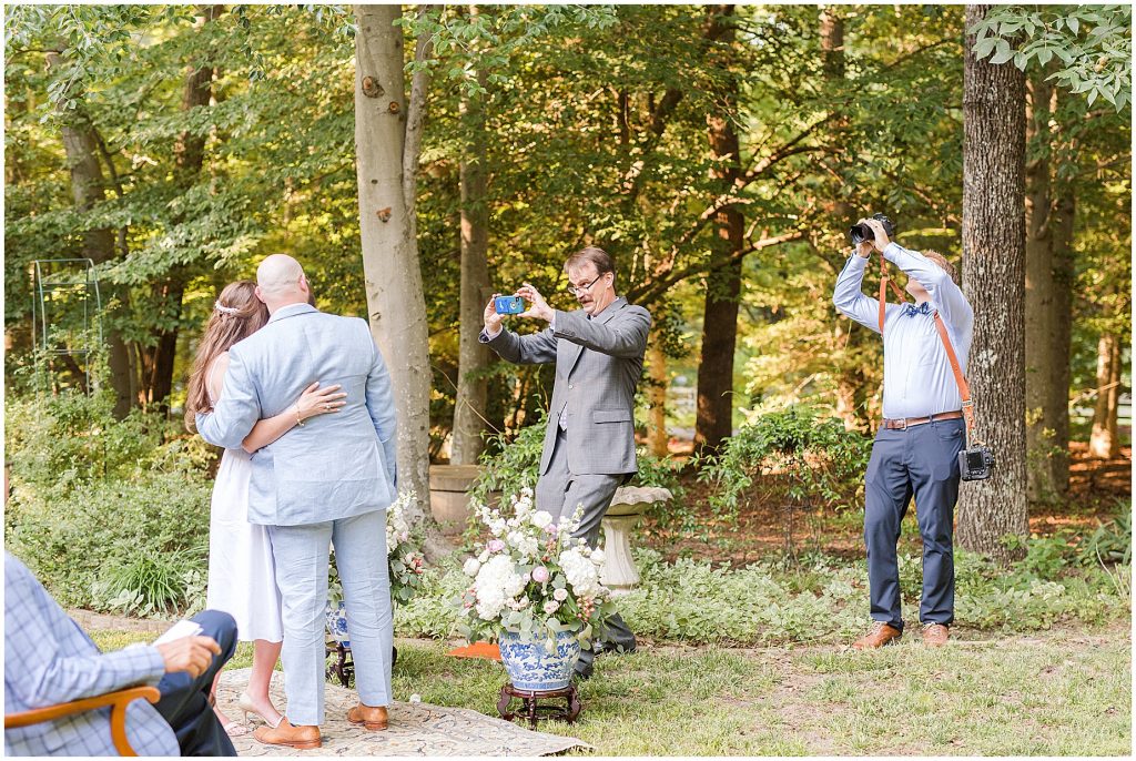 photographer taking a couple photo over shoulder of officiant at ceremony