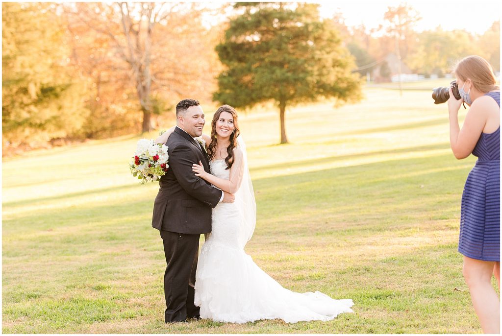 bride and groom with photographer in a field at sunset at amber grove in Richmond, Varlottesville