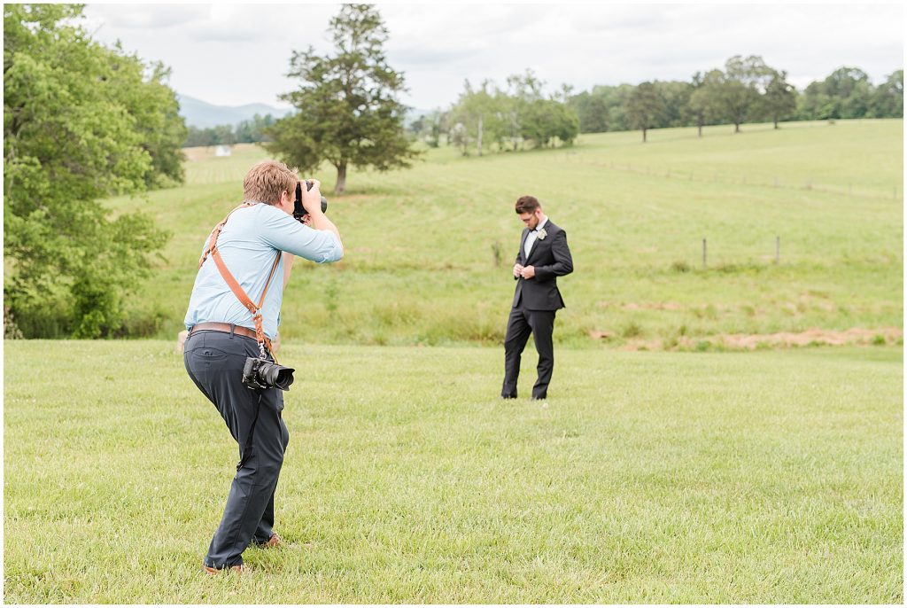 groom with photographer in a field at edgewood barn in Charlottesville