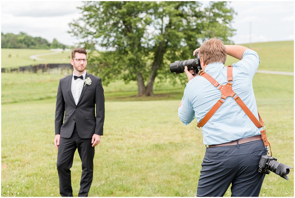 groom with photographer in a field at edgewood barn in Charlottesville
