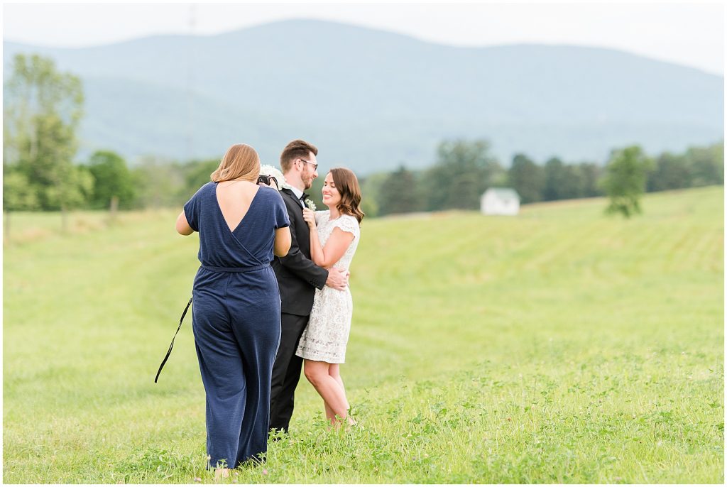 bride and groom with photographer in a field at edgewood barn in Charlottesville