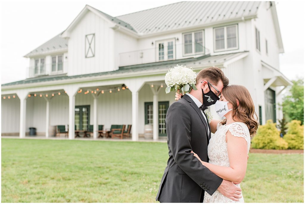 coronavirus mini wedding bride and groom with just married masks in front of barn at edgewood